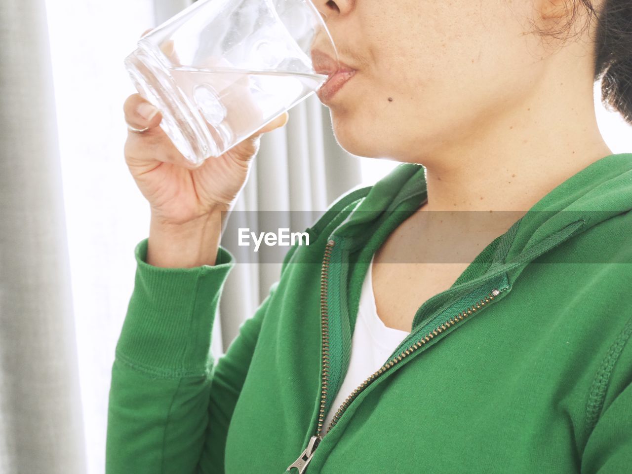 Midsection of woman drinking water at home