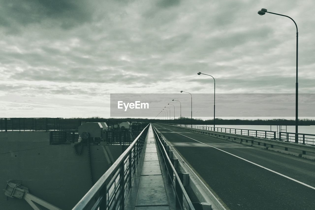 Road on bridge against cloudy sky