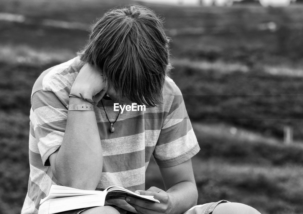 Teenage boy studying on field