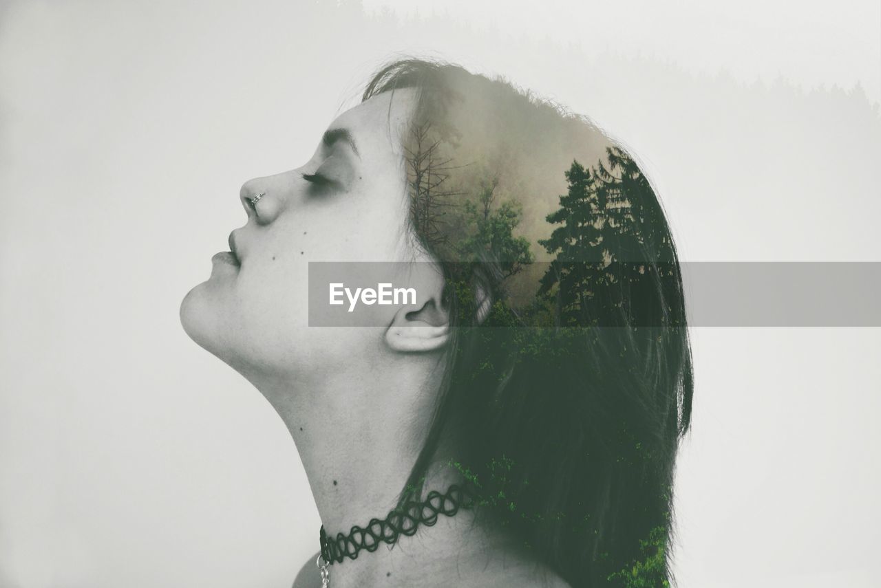 Double exposure image of woman and forest against white background