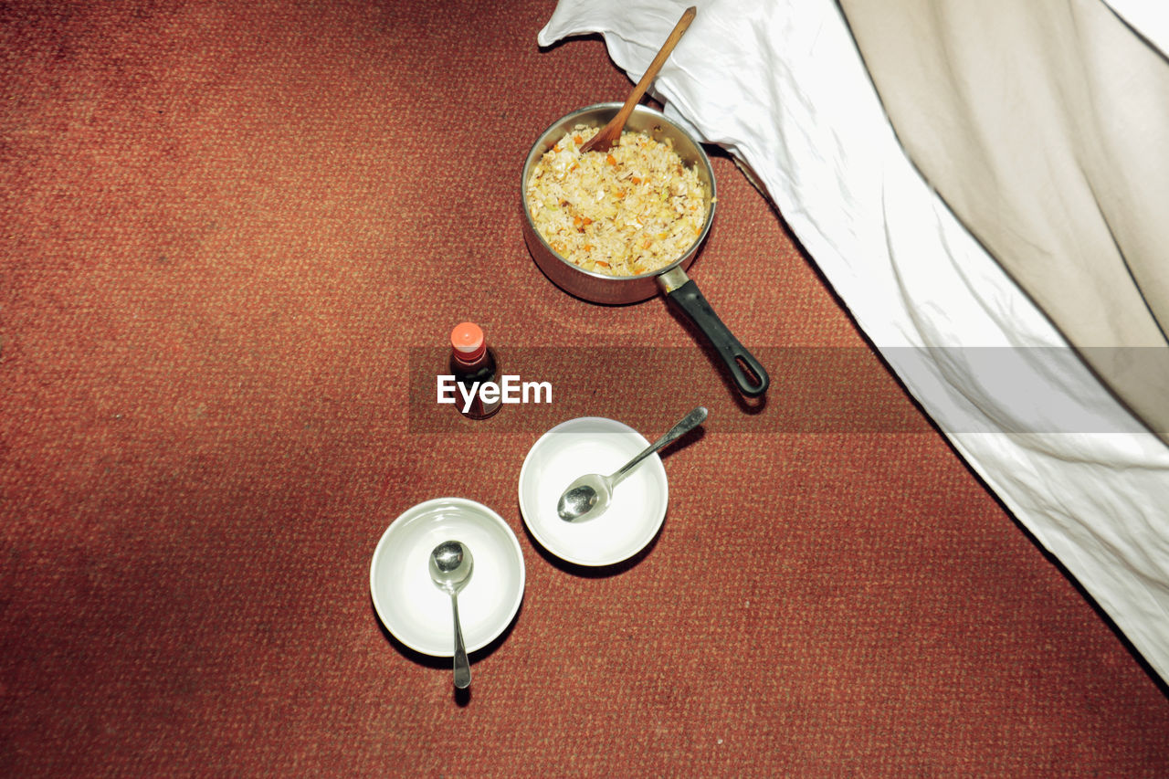 High angle view of food in a pan and two plates in the carpet