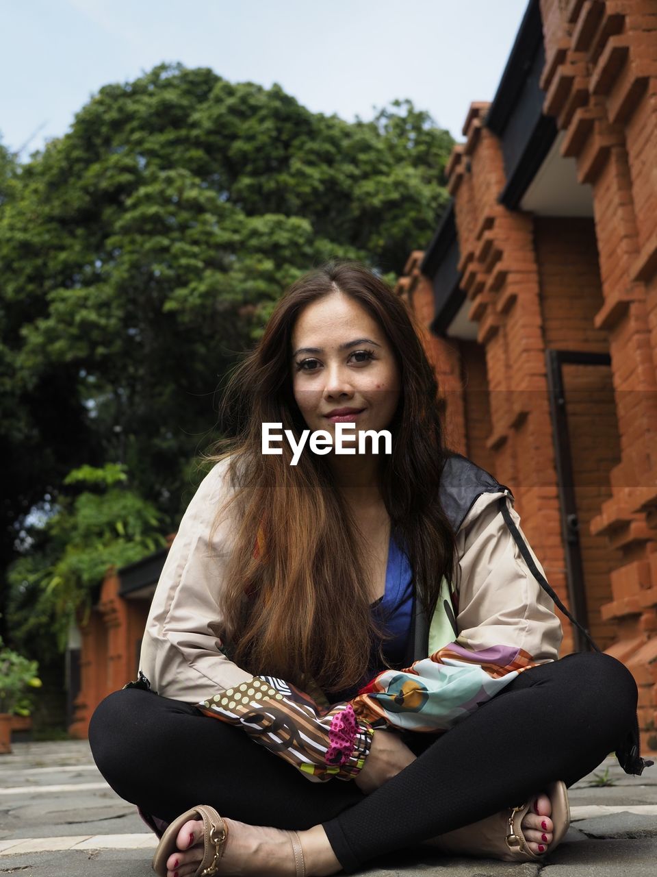 Portrait of smiling woman sitting on footpath