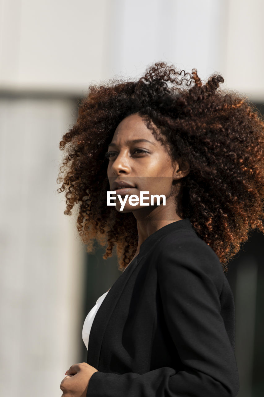 Side view of thoughtful young woman with frizzy hair