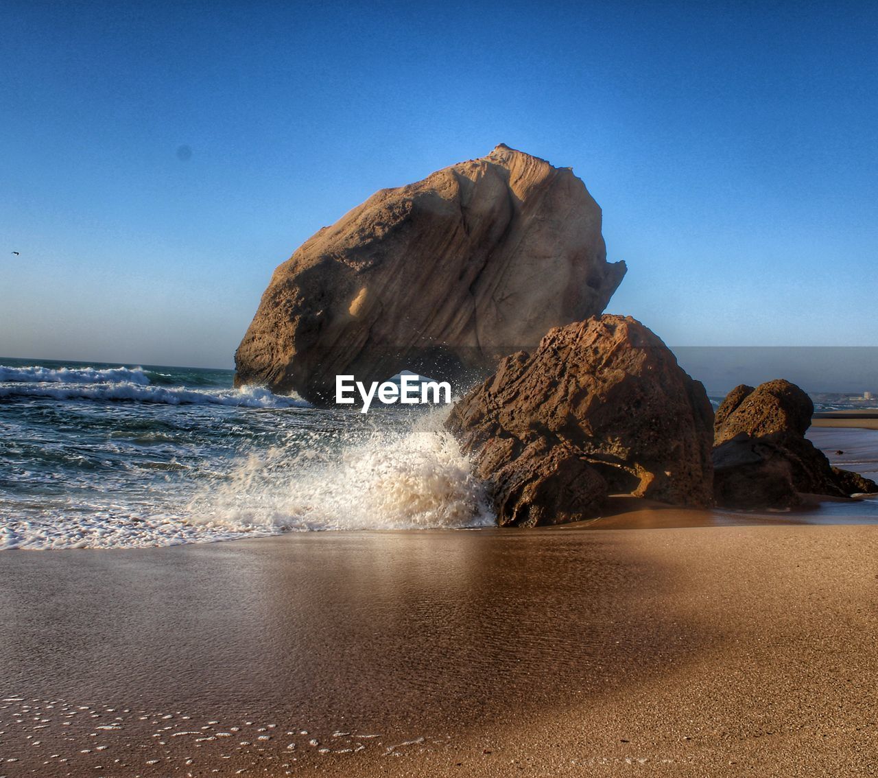 ROCK FORMATION ON BEACH AGAINST SKY