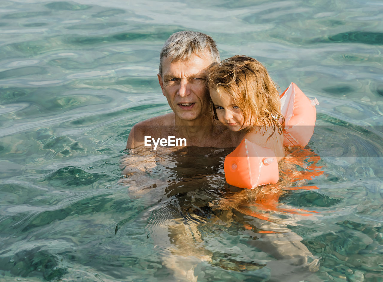 High angle view of grandfather with child swimming in pool