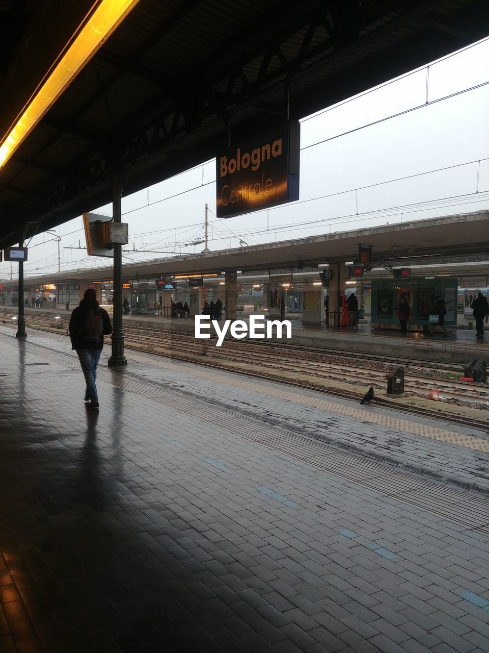 MAN WALKING AT RAILROAD STATION