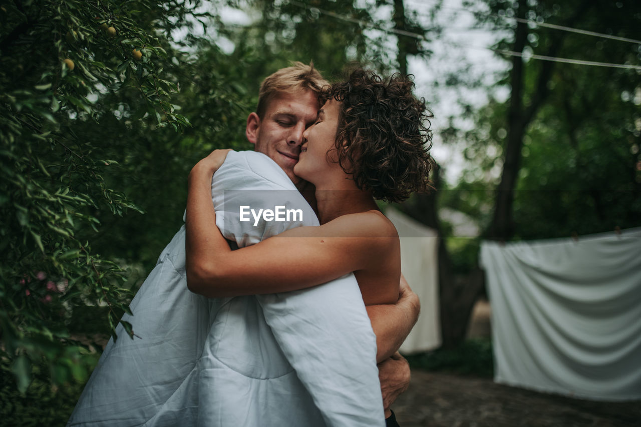 Young couple kissing against trees