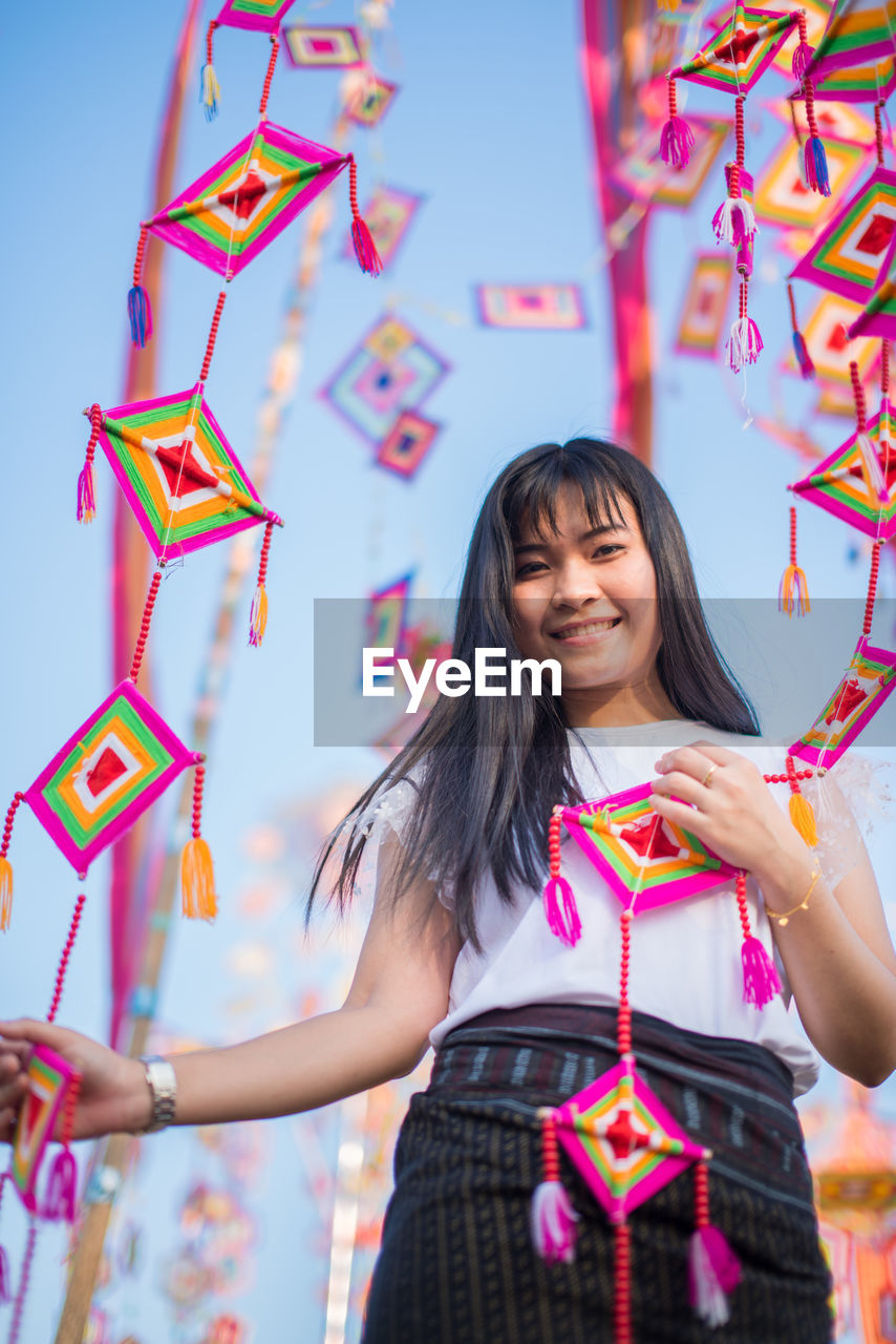 Portrait of smiling woman holding colorful decorations