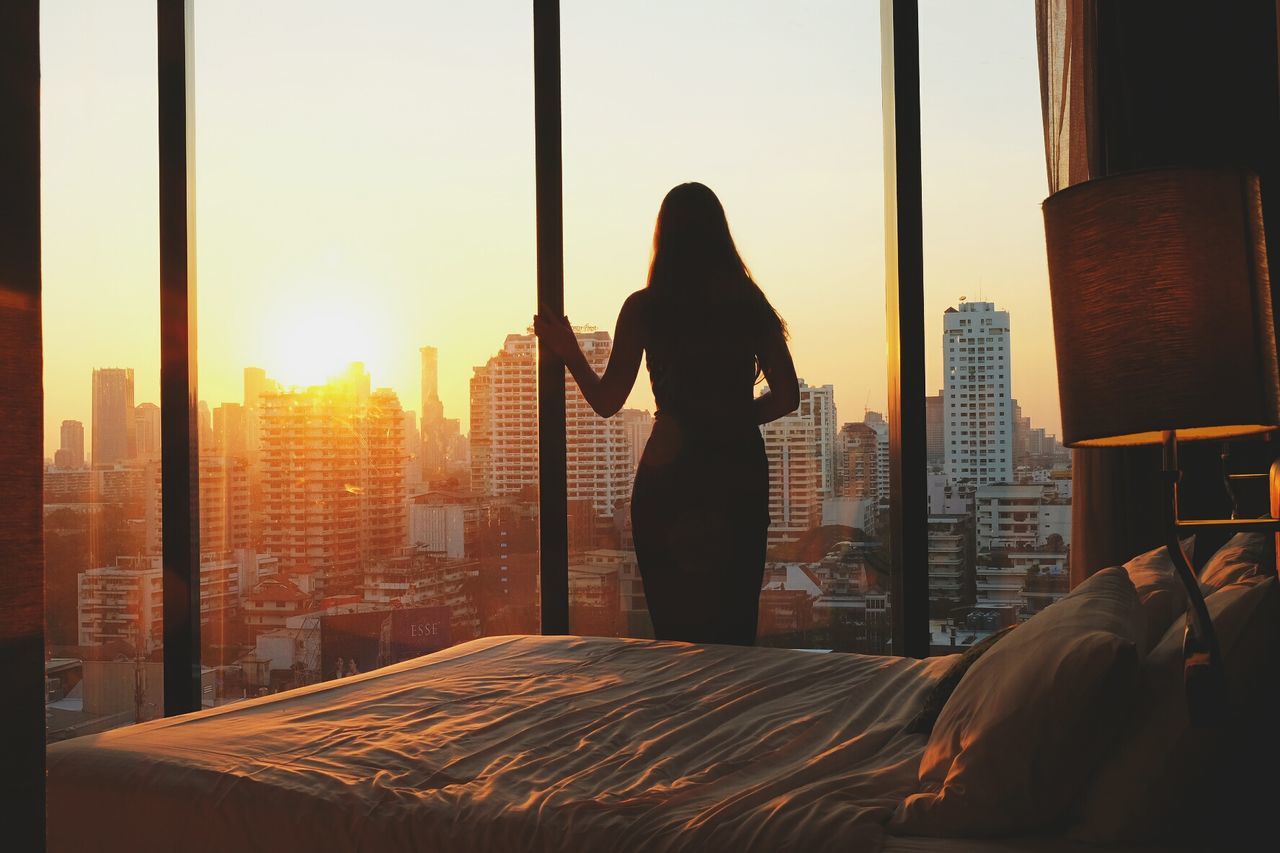 WOMAN STANDING IN CITY AT SUNSET