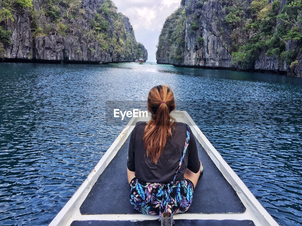 Rear view of woman sitting on boat looking at view of sea