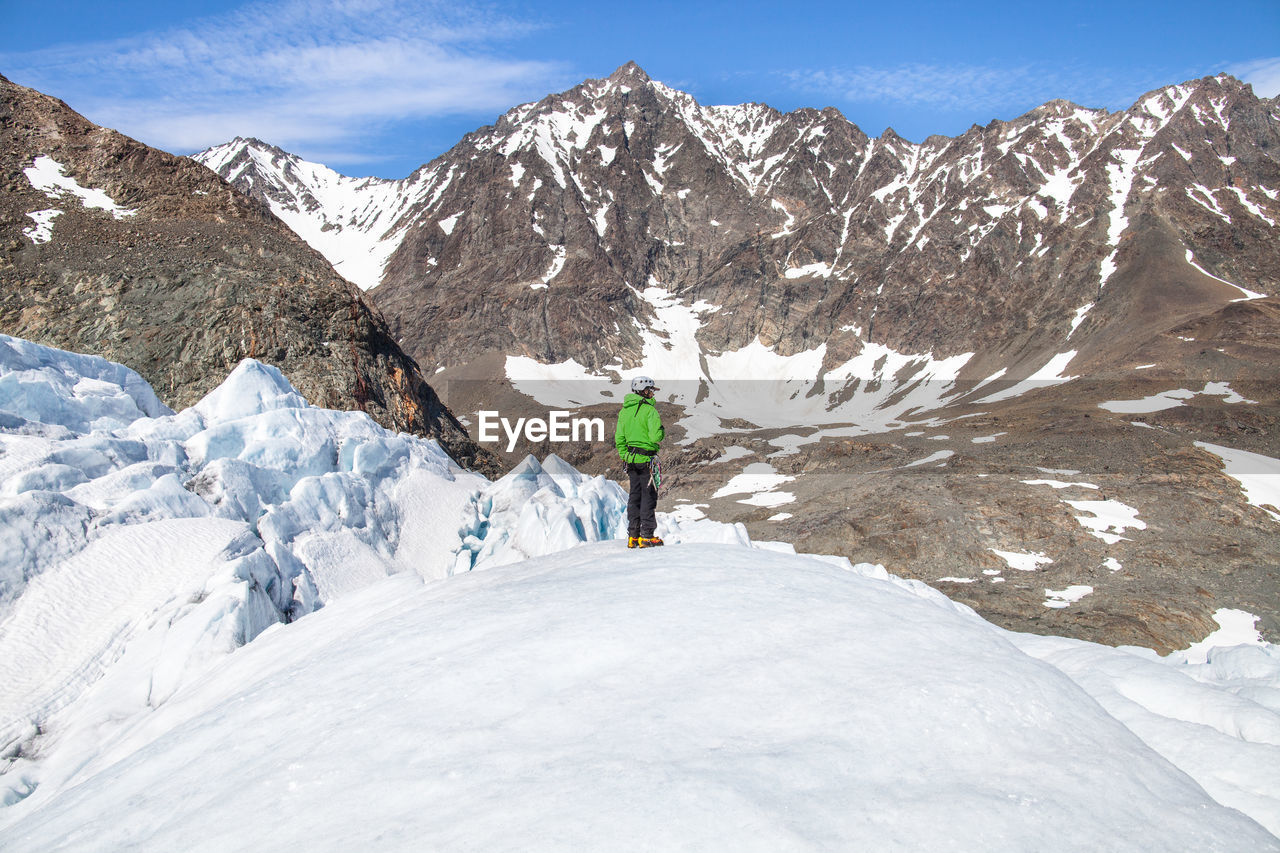 Person standing on snow covered landscape against mountain range