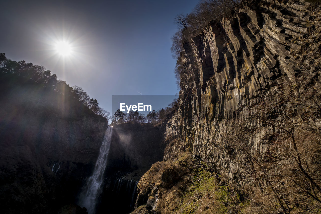 LOW ANGLE VIEW OF WATERFALL AGAINST SKY DURING SUNNY DAY