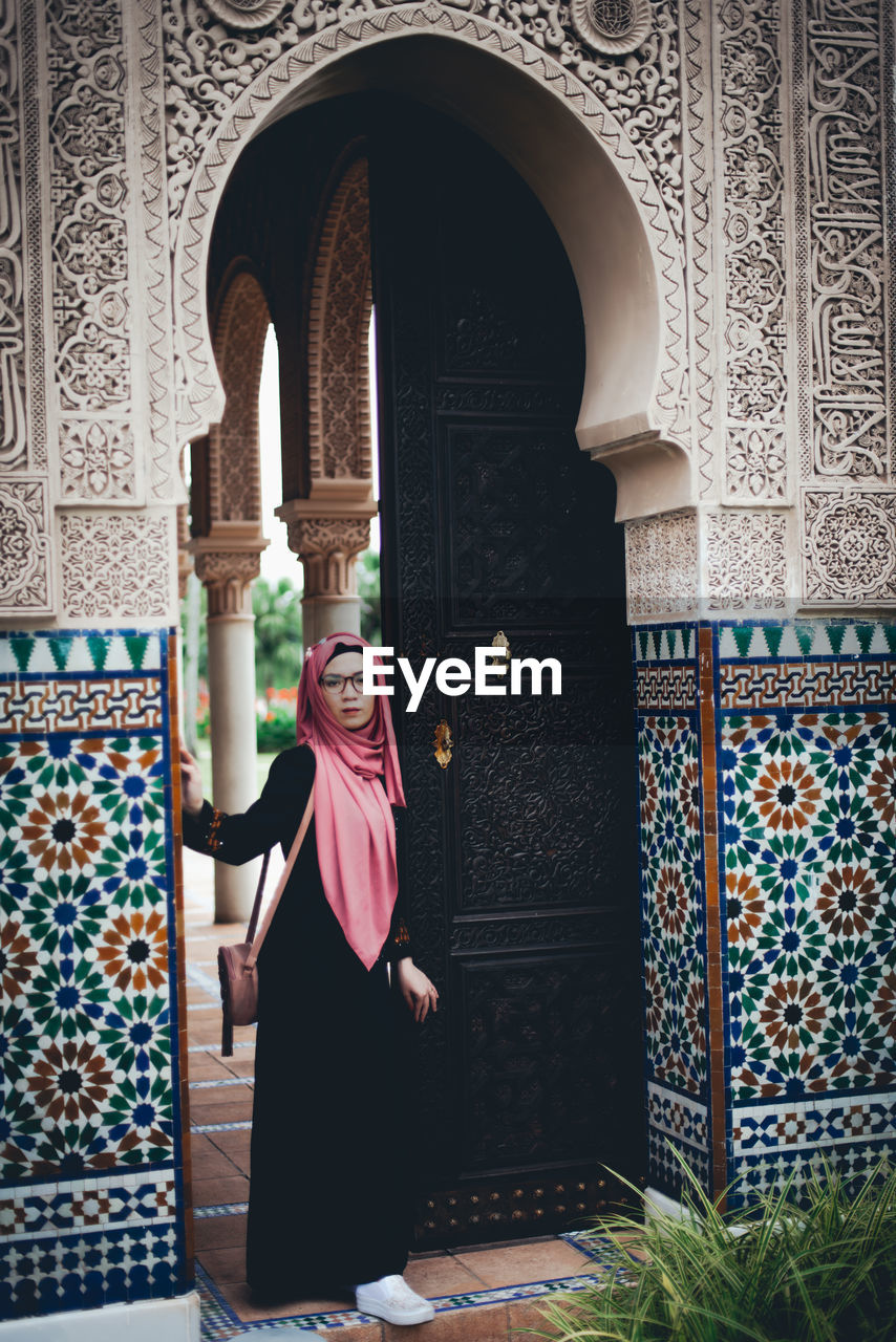 Portrait of woman standing at entrance of historic building