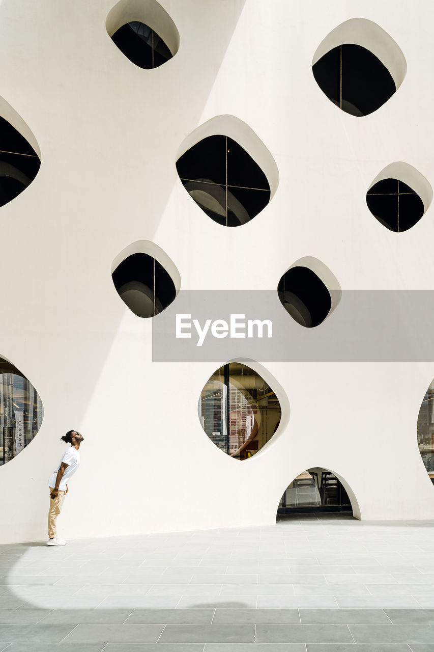 LOW ANGLE VIEW OF MAN WALKING ON MODERN BUILDING