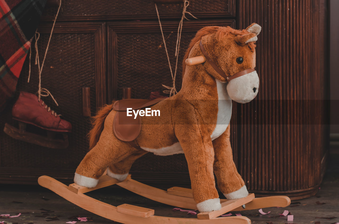 Soft children's rocking horse on the background of an old chest of drawers