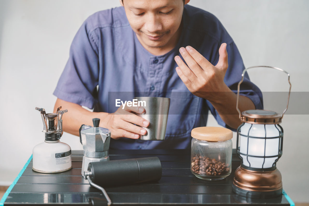 midsection of man using mobile phone while sitting on table