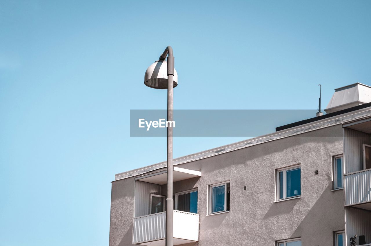 Low angle view of street light against building against clear sky