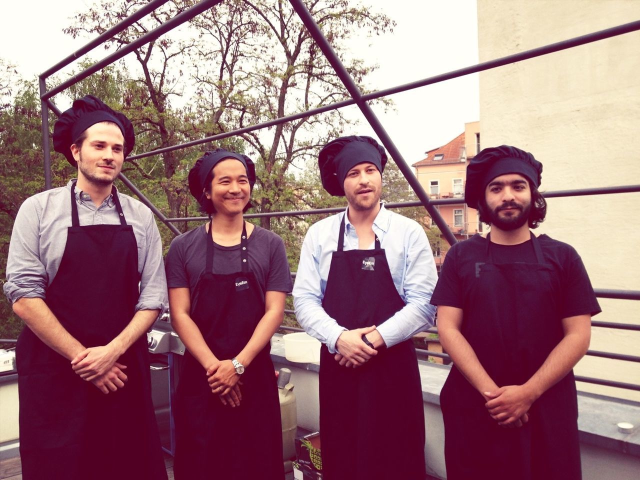 Four young men dressed as chefs standing outdoors