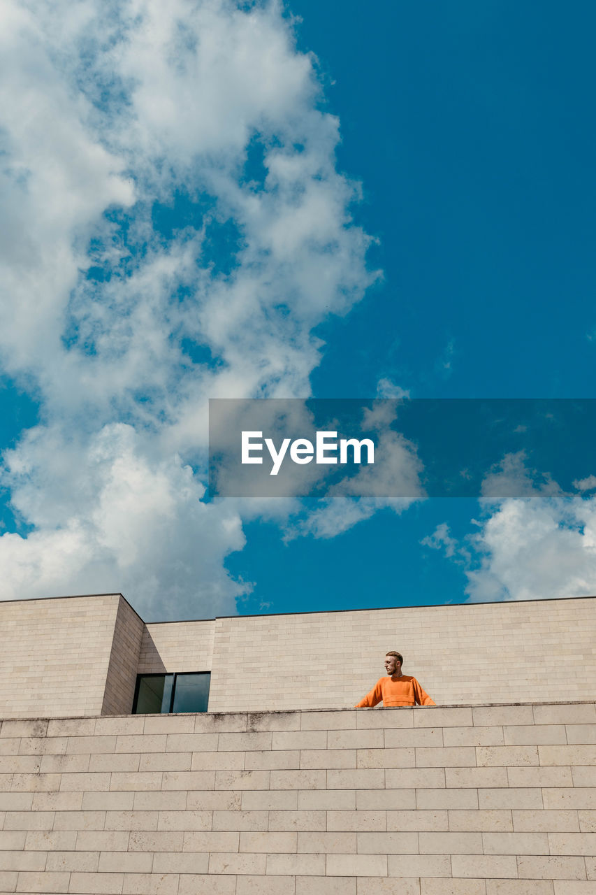 Low angle view of man standing at building terrace