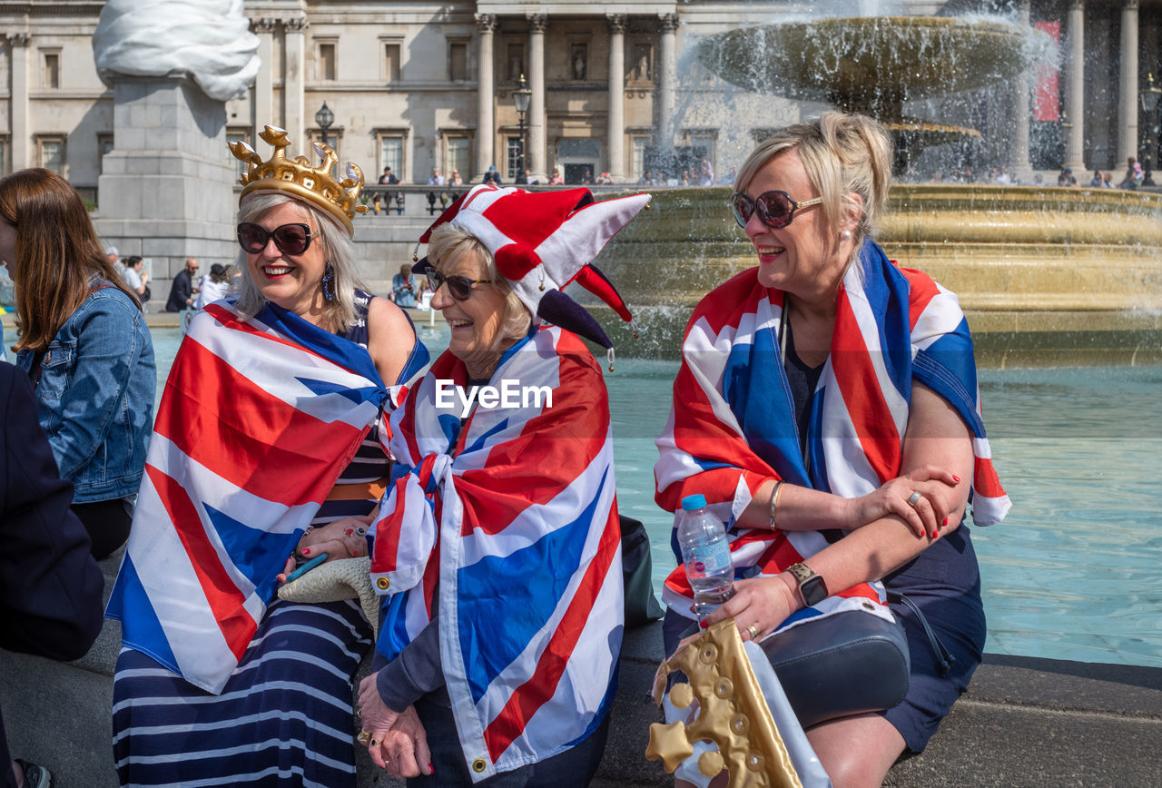 group of people, adult, women, men, architecture, water, flag, day, crowd, female, building exterior, togetherness, young adult, festival, emotion, built structure, sitting, transportation, nautical vessel, happiness, mature adult, outdoors, celebration, person, city, clothing, smiling, travel, social group, travel destinations, nature