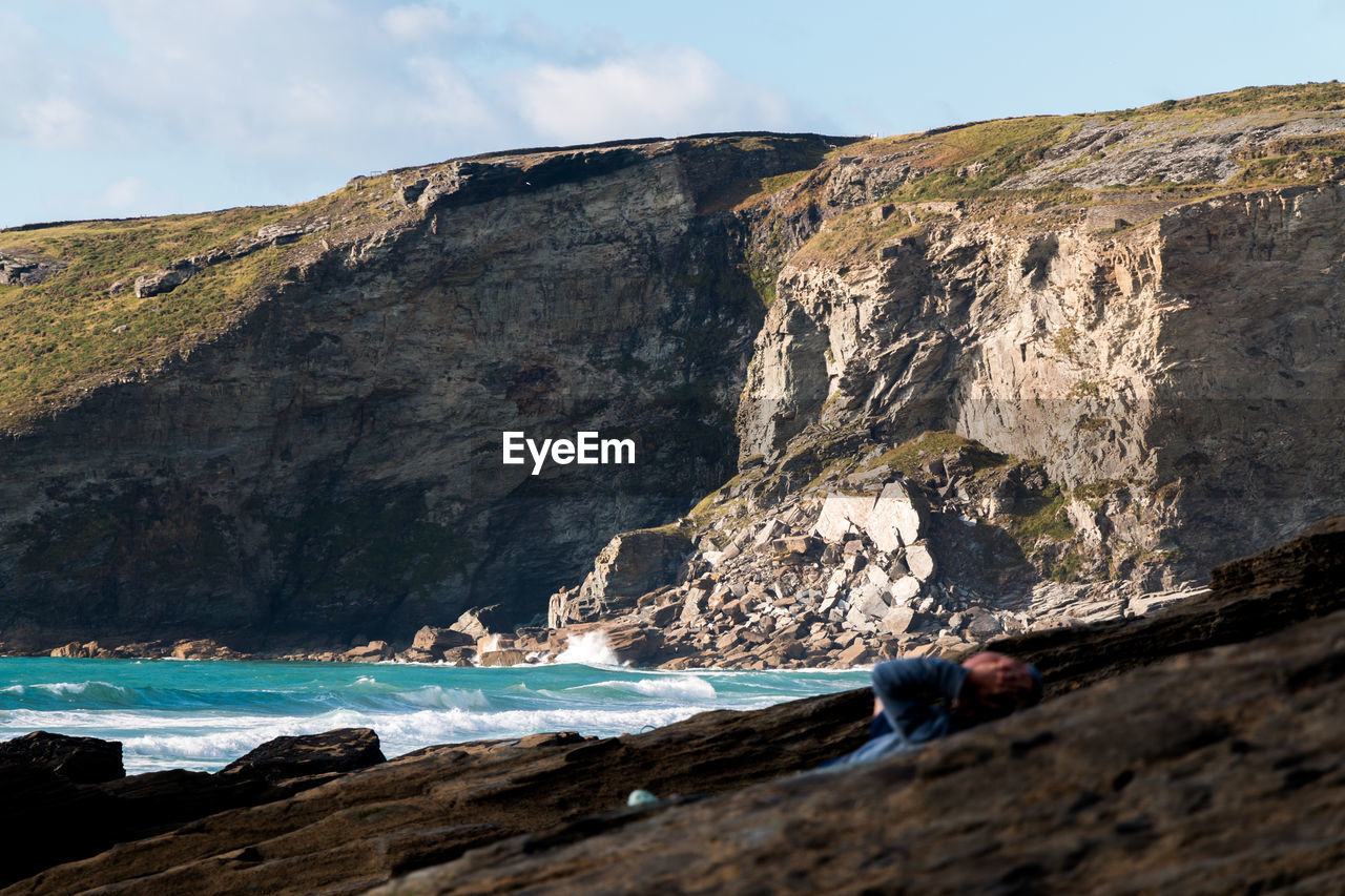 Rock formation by sea against sky