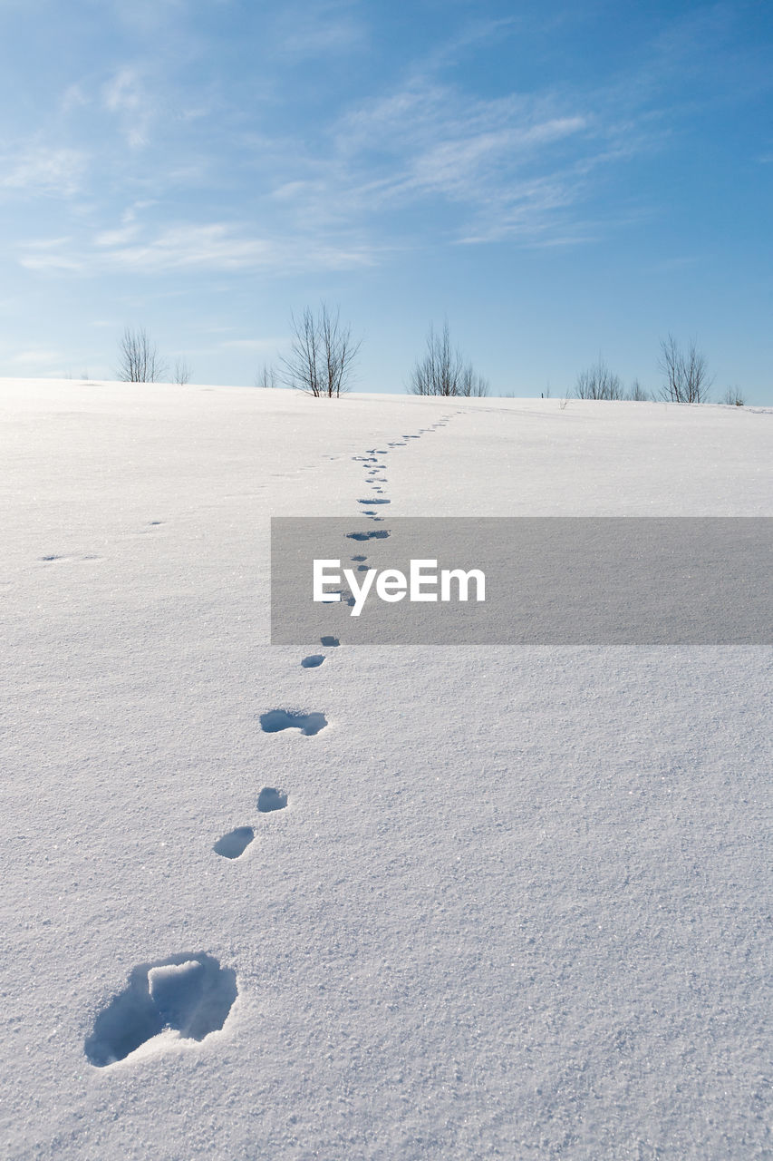 FOOTPRINTS ON SNOW LANDSCAPE AGAINST SKY