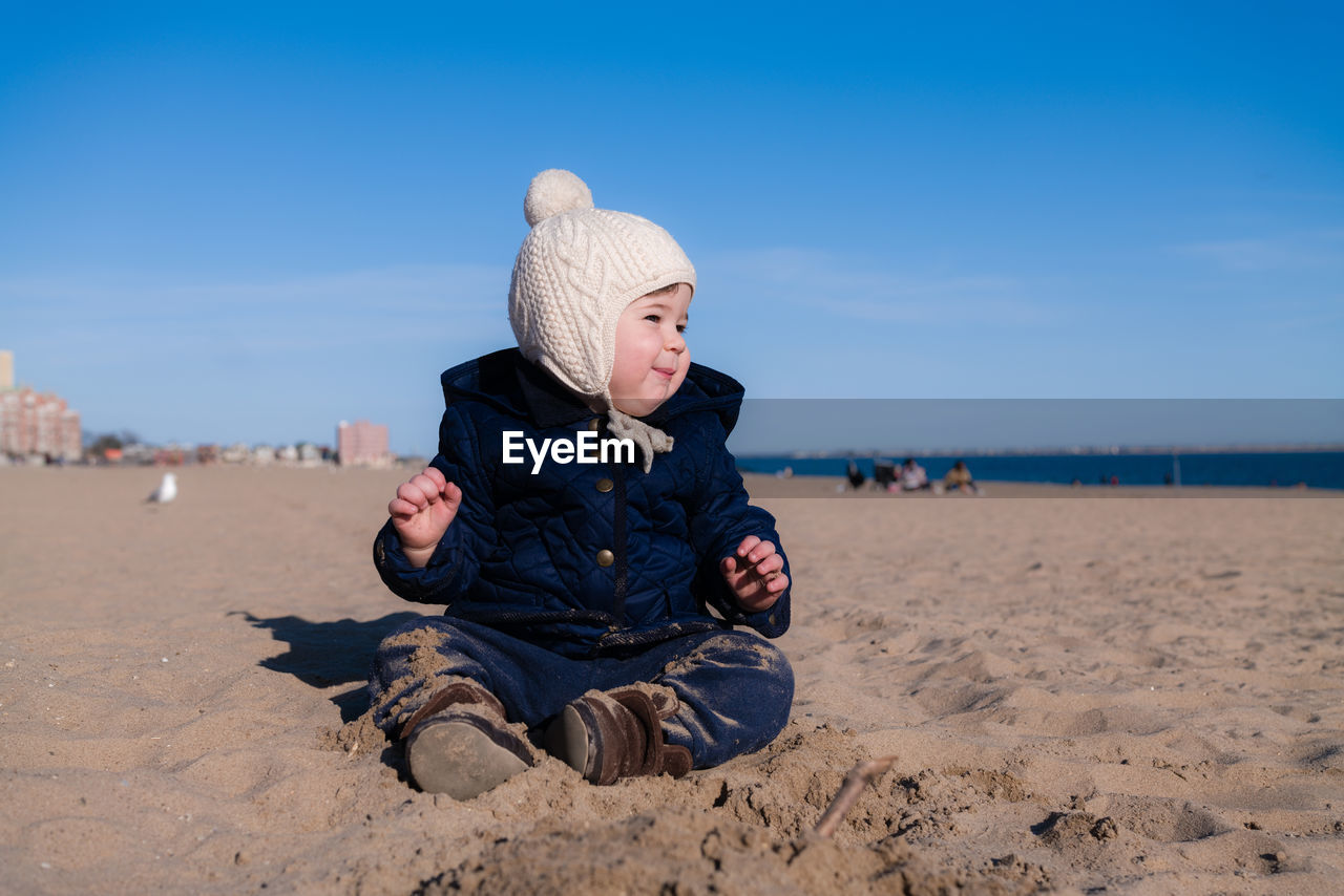 Extatic young boy is playing in the sand during in cold weather