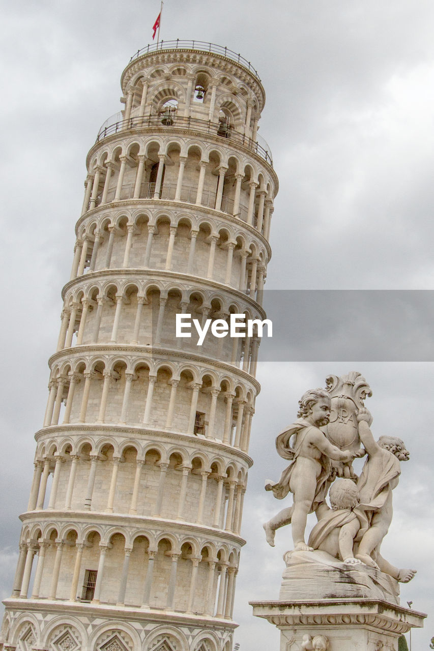 Leaning tower of pisa and statue against sky