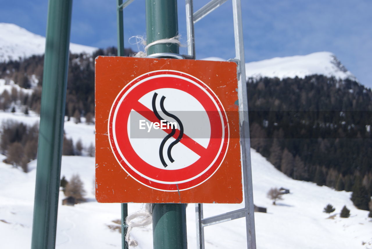 CLOSE-UP OF ROAD SIGN ON SNOW COVERED FIELD