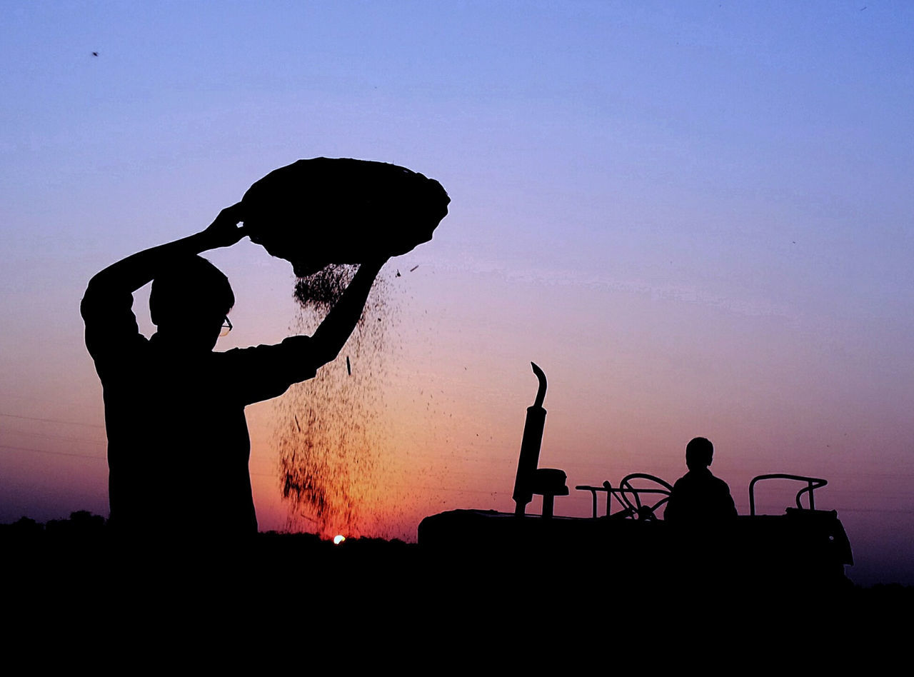 Silhouette man pouring sand against sky during sunset