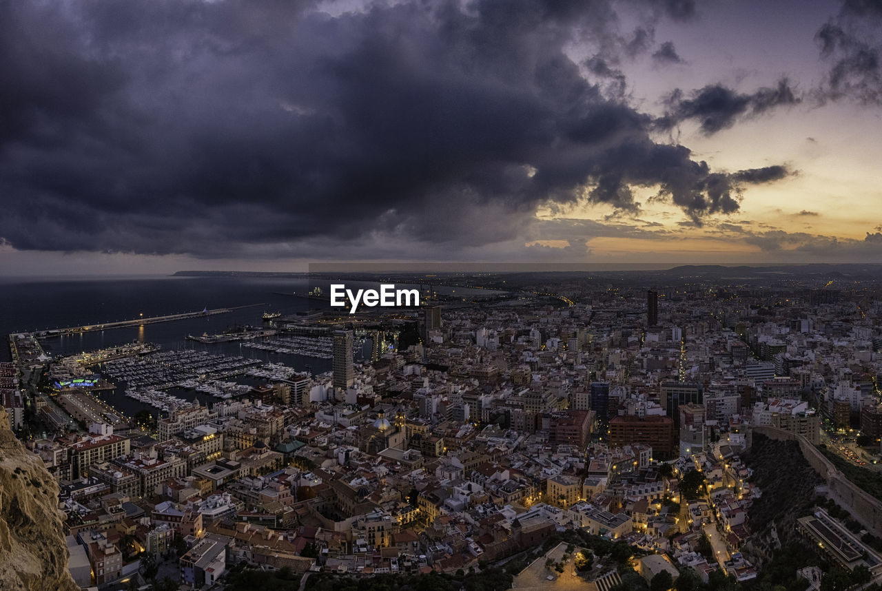 Aerial view of city against cloudy sky during sunset