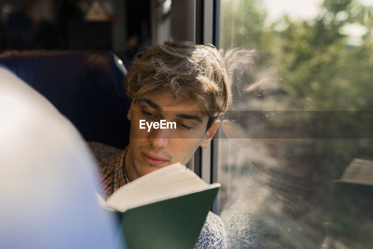 Young man reading book in a train