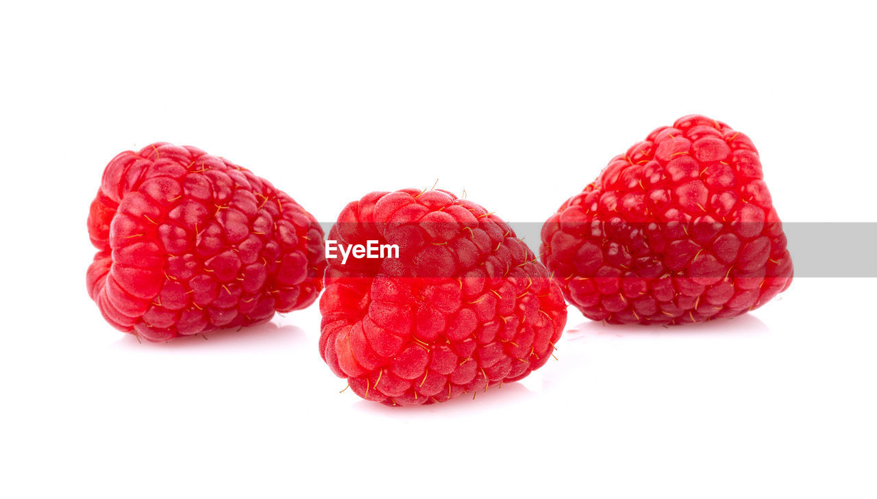 CLOSE-UP OF RASPBERRIES AGAINST WHITE BACKGROUND