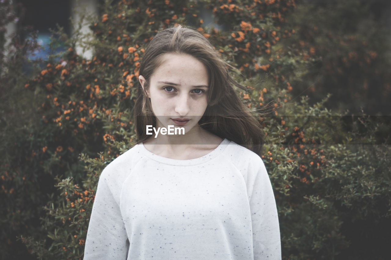 Portrait of teenage girl standing against plants during autumn