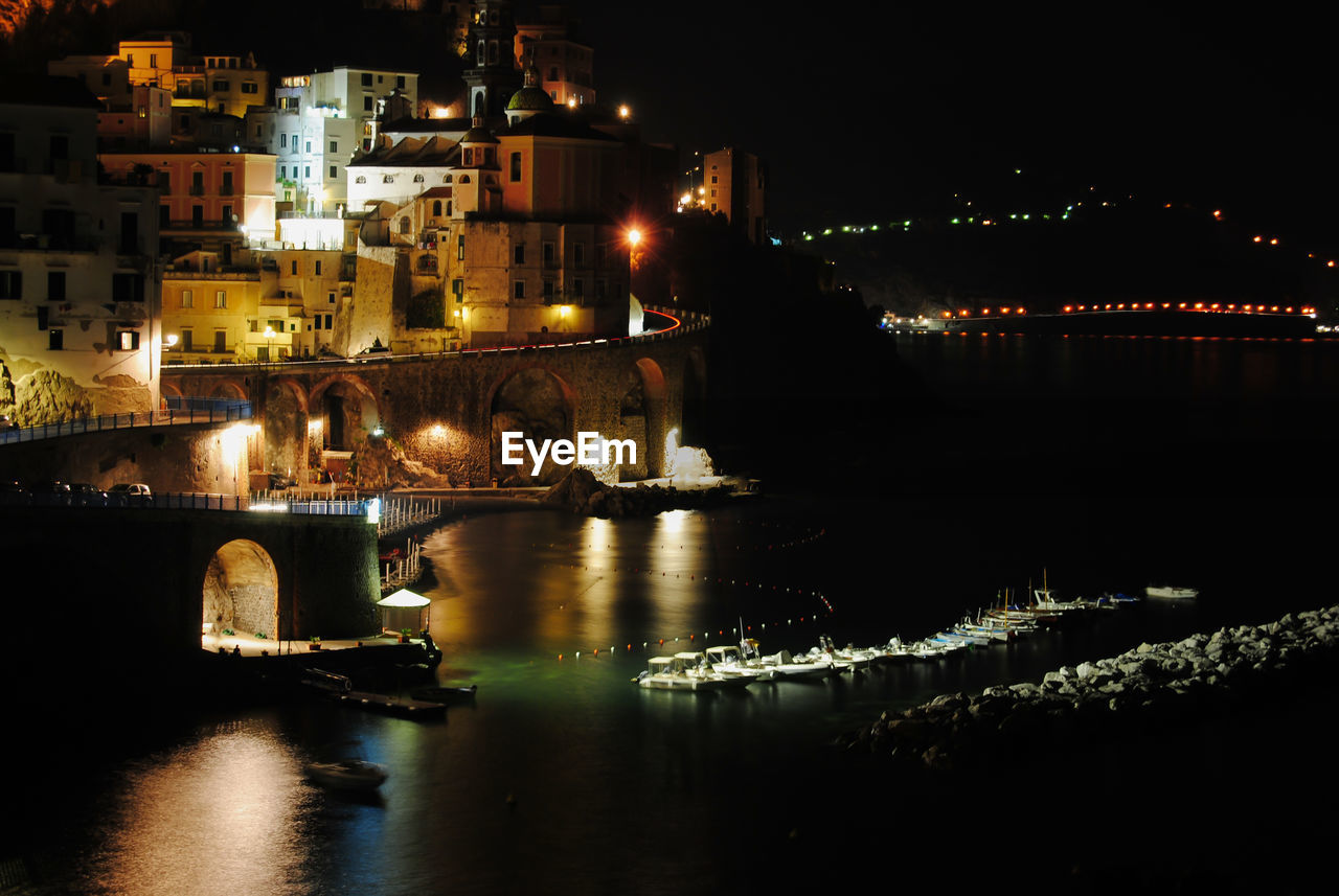 Night view of atrani from amalfi and reflections over the sea with boats moored