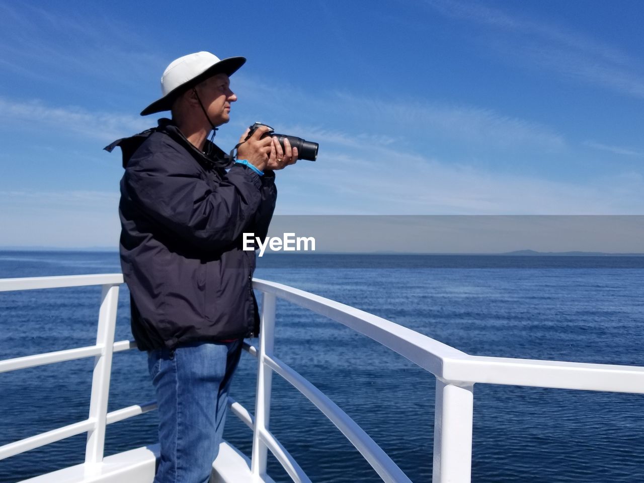 WOMAN STANDING ON RAILING AGAINST SEA