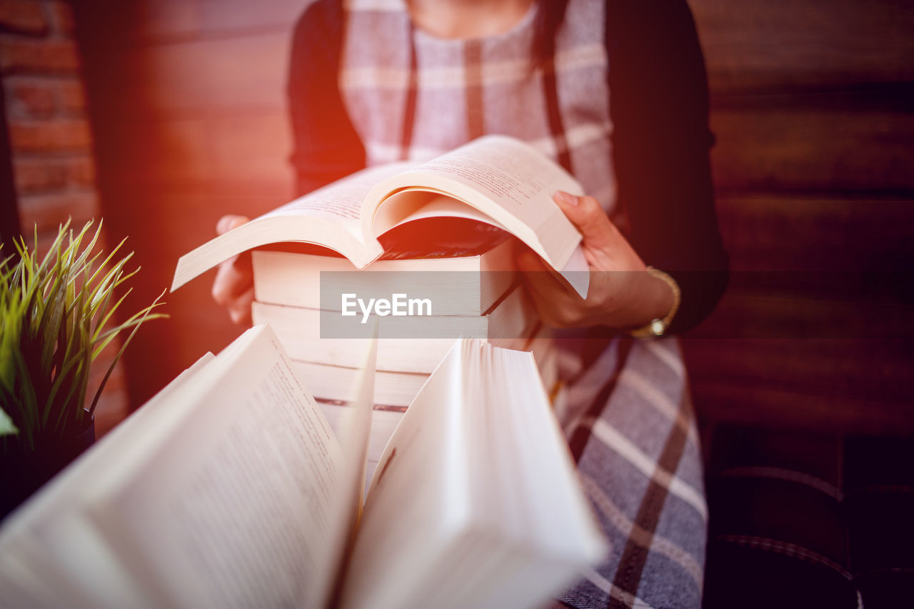 Midsection of woman reading book at home