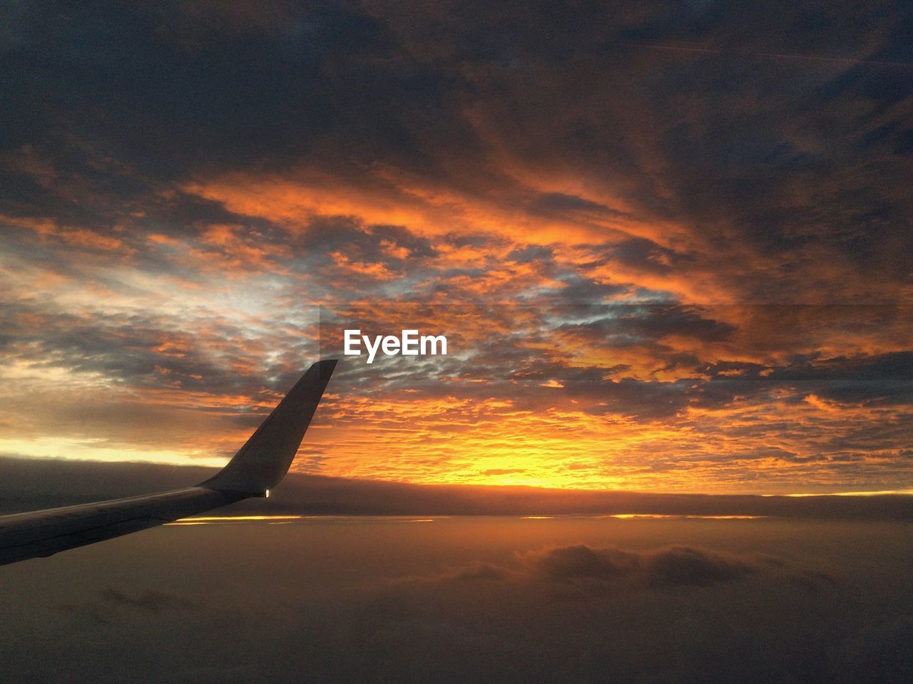 Airplane flying over cloudscape during sunset