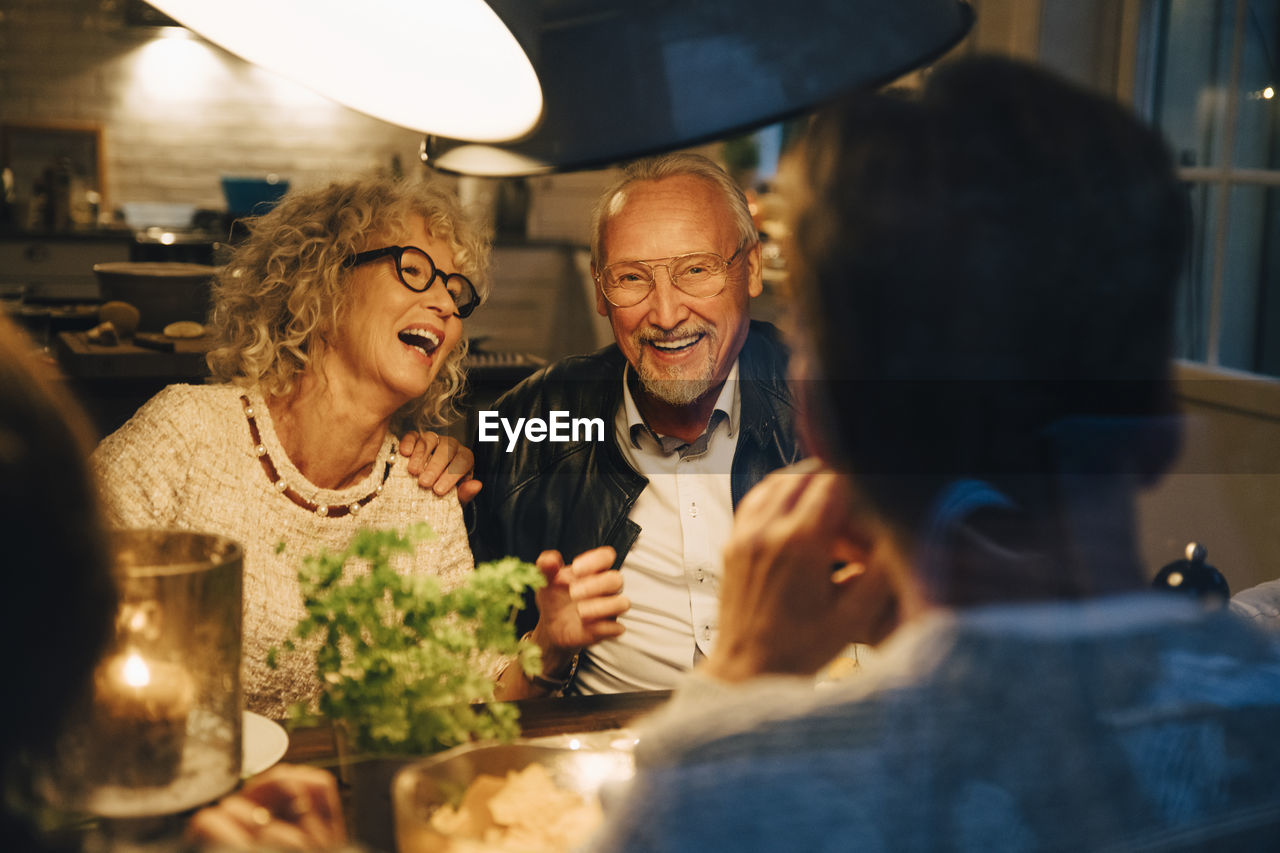 Cheerful senior friends enjoying dinner party at home