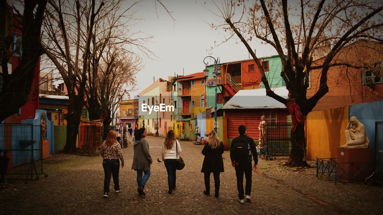 PEOPLE WALKING ON ROAD ALONG BUILDINGS