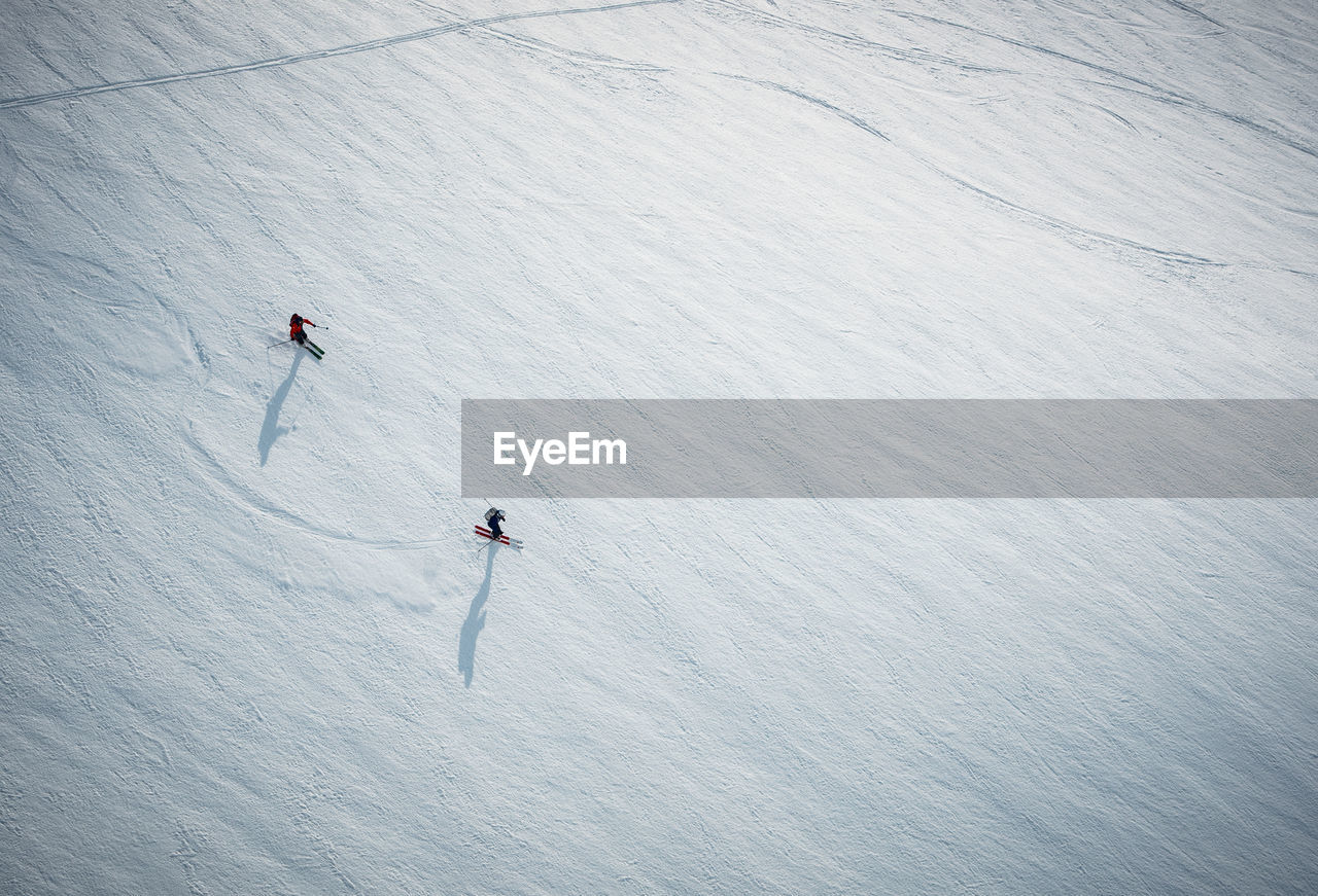 Two men skiing on snow in iceland from overhead angle