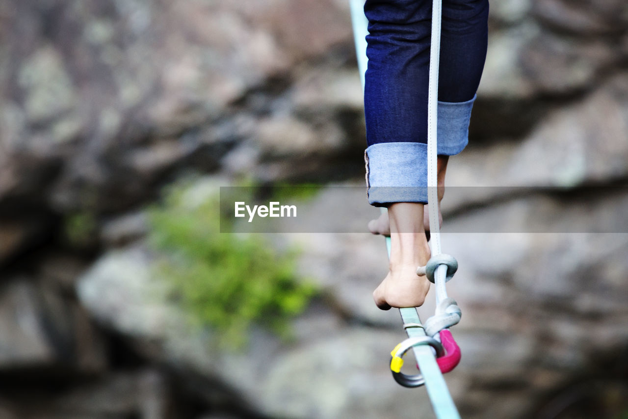 Low section of woman walking on rope against rocks