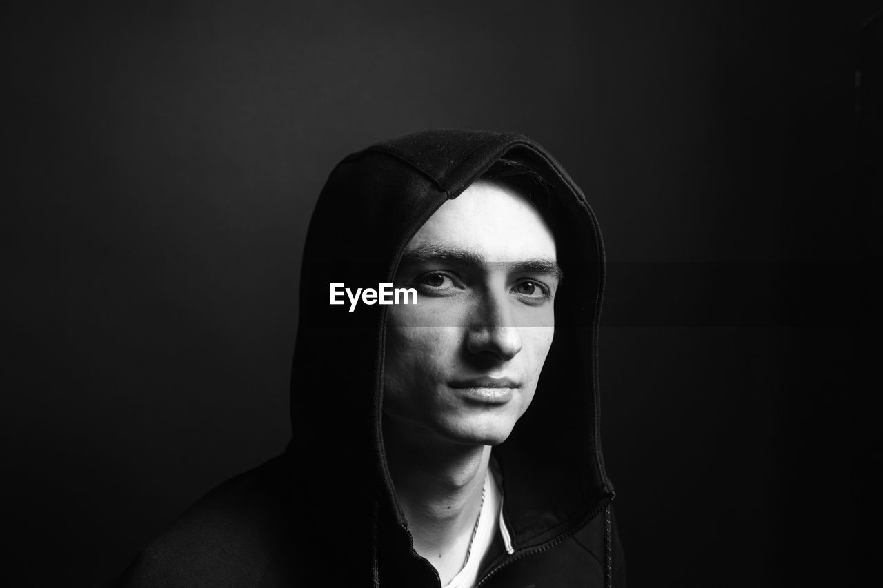 Portrait of young man against black background