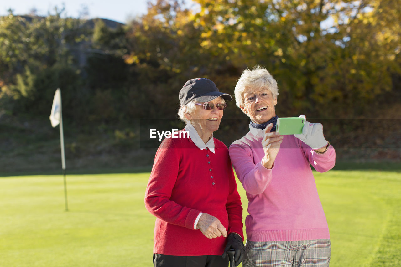 Senior female golfers photographing on golf course