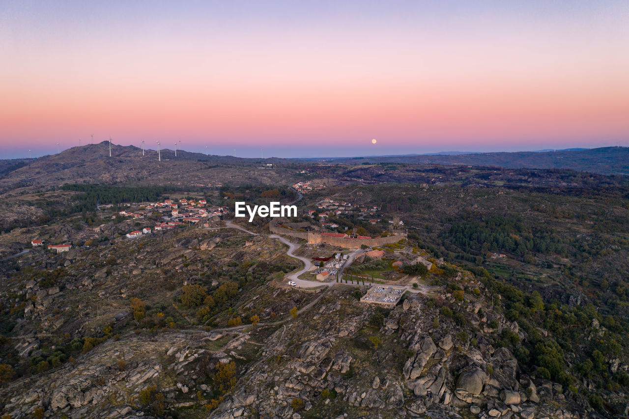 Drone aerial panorama of sortelha historic village at sunset wind turbines and nature landscape
