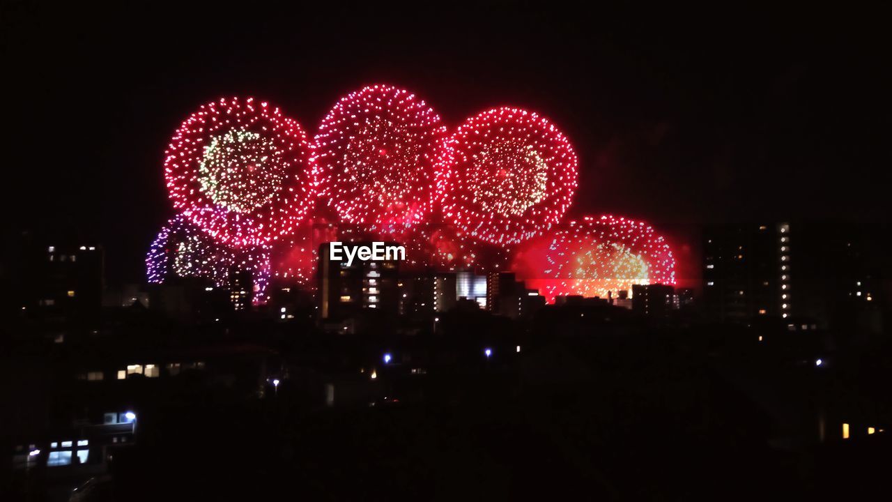 FIREWORK DISPLAY IN CITY AGAINST SKY AT NIGHT