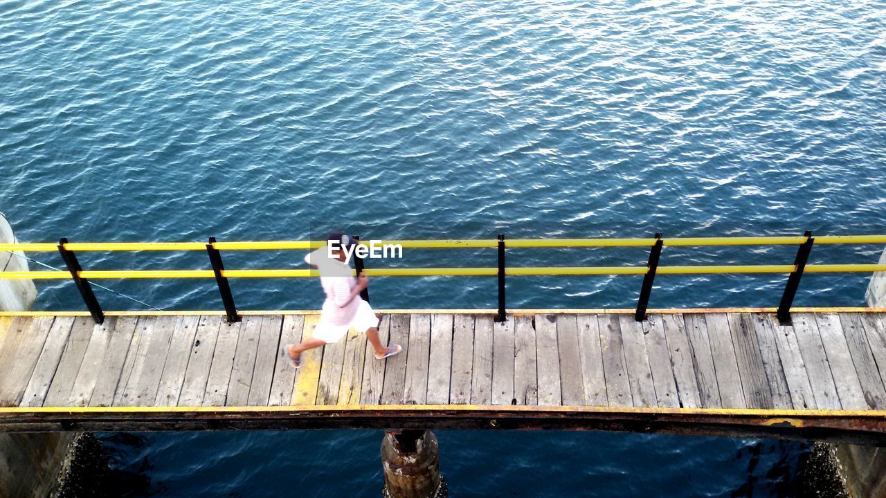 High angle view of man running on footbridge over lake