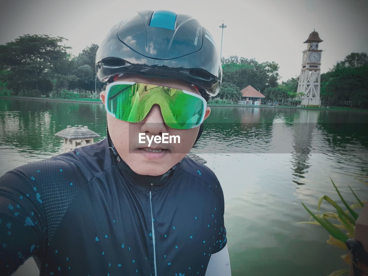 PORTRAIT OF MAN WEARING SUNGLASSES AGAINST LAKE