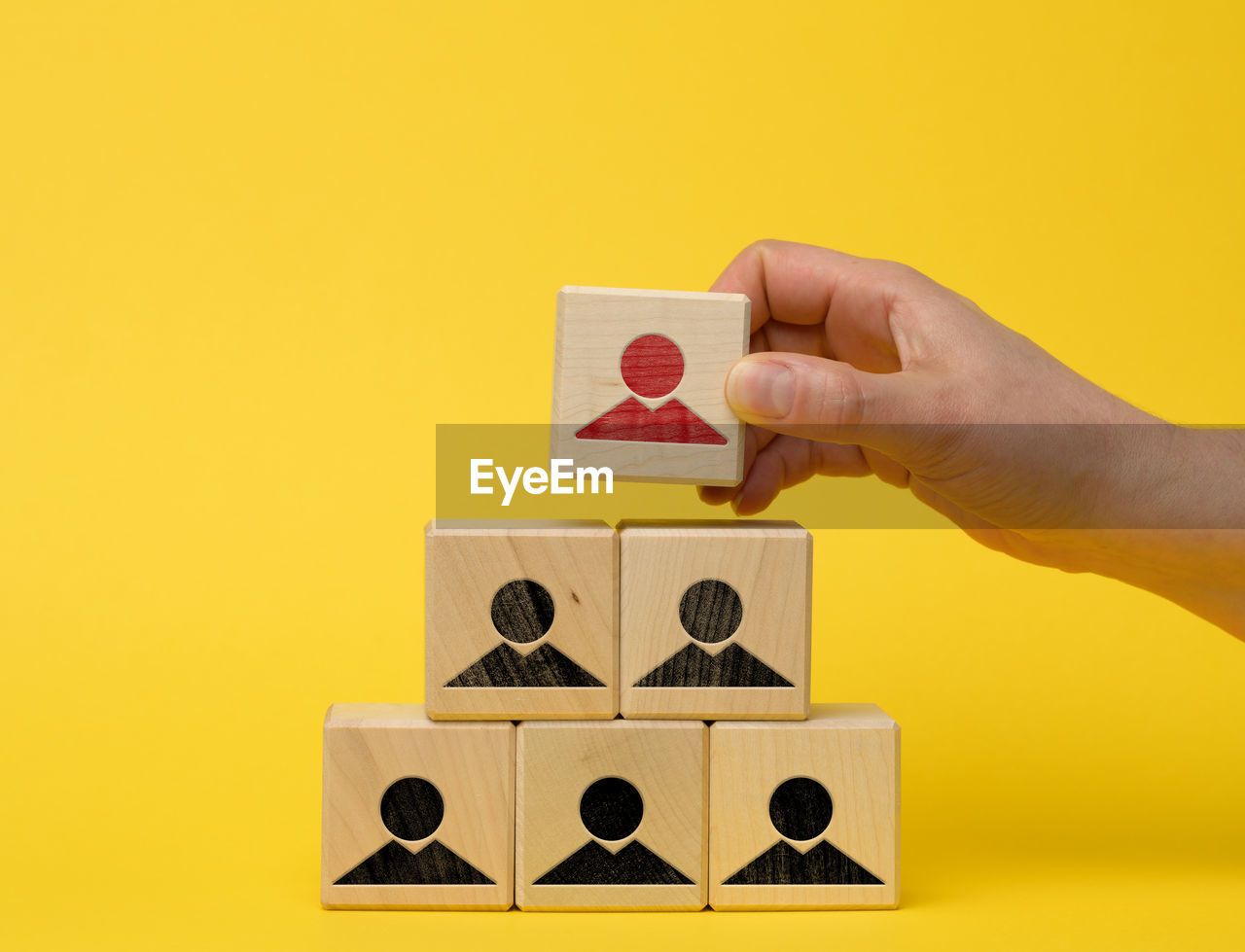 Female hand holds a wooden block on a blue background. recruitment concept, teamwork, 