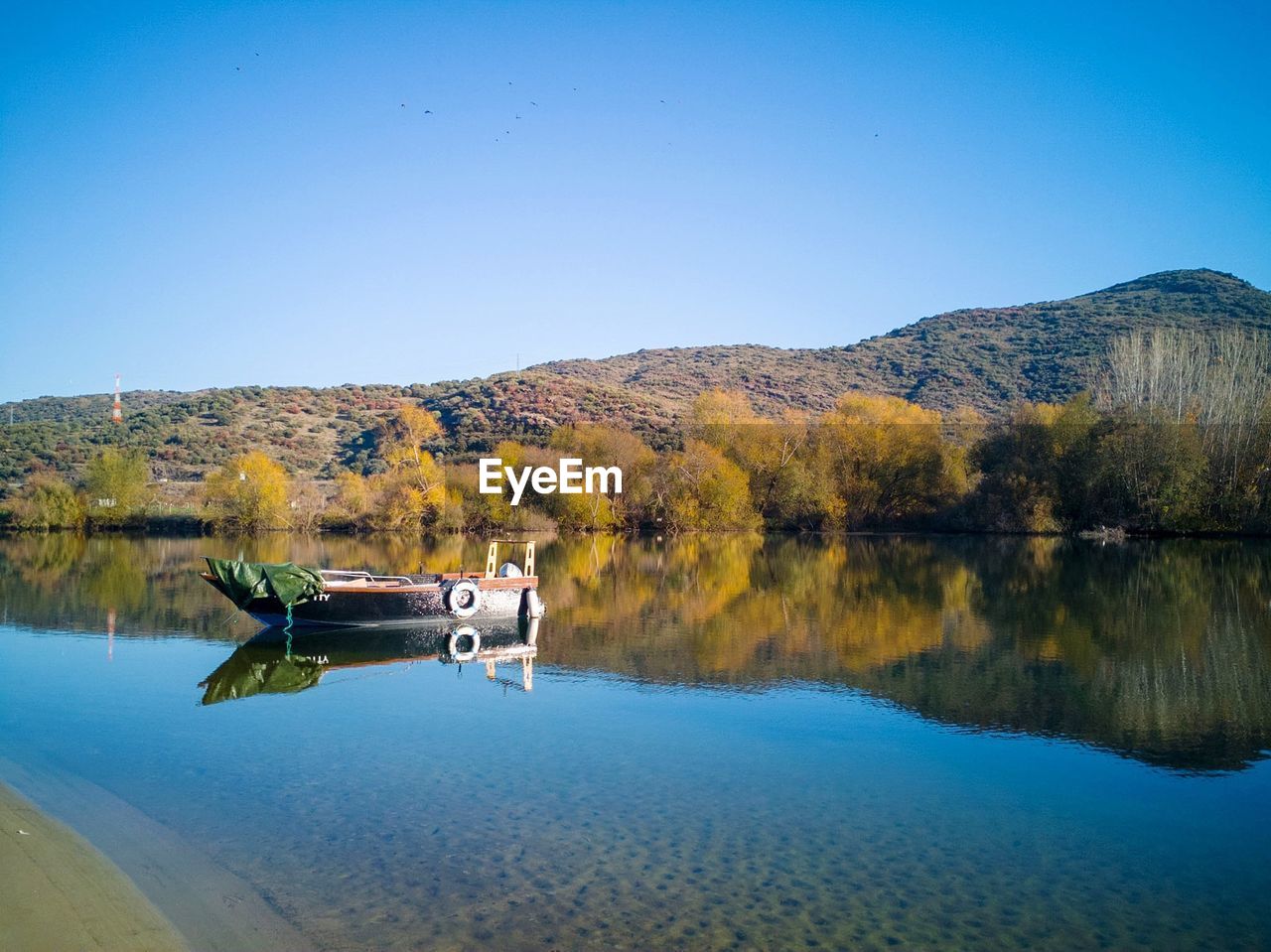 Boat in lake against clear blue sky